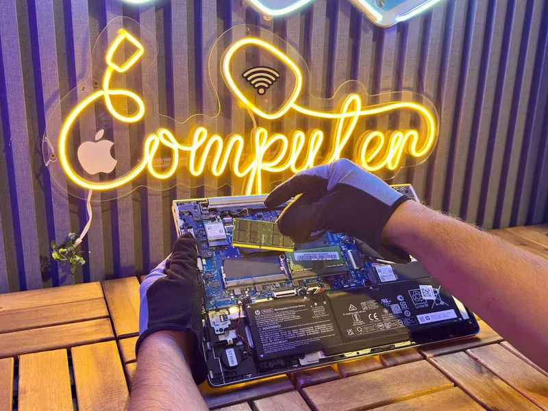 Manos con guantes instalando un módulo de memoria RAM en una laptop