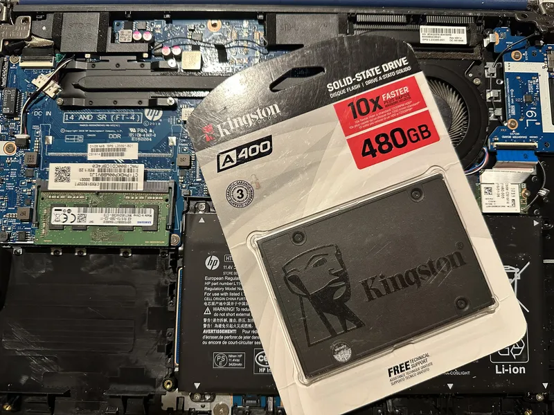 Unidad SSD nueva en su empaque sobre el interior de una laptop abierta