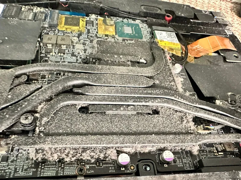 Interior de una laptop con polvo acumulado sobre los tubos del disipador, antes de la limpieza