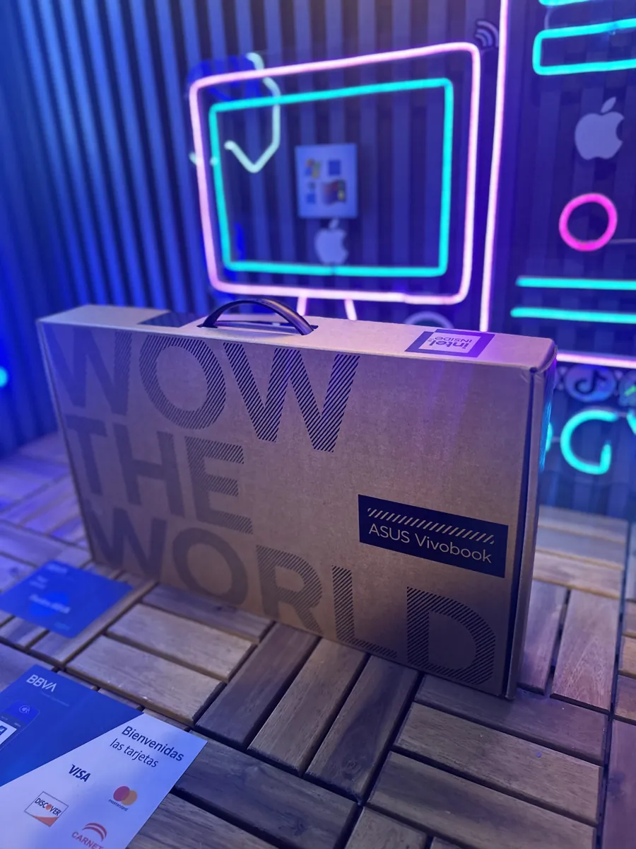 Caja de una laptop nueva con asa, junto a un letrero de pago con tarjeta